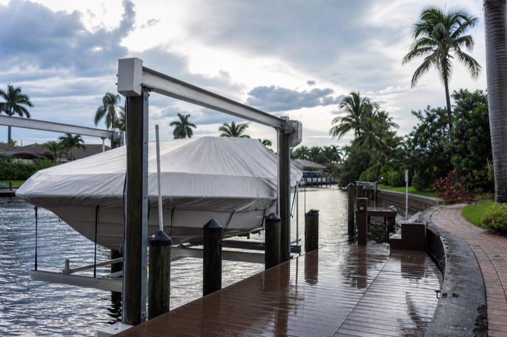 Marine-grade four-post boat lift cradling a center console above a Southwest Florida canal